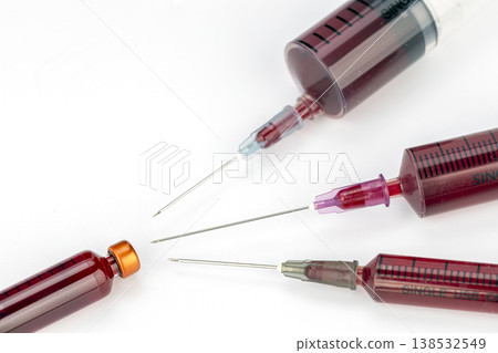 Close-Up of Multiple Single-Use Medical Syringes Filled With Dark Red Blood, Featuring Exposed Sharp Needles Arranged on a Clean White Studio Background Close-Up of Multiple Single-Use Medical Syringes Filled With Dark Red Blood, Featuring Exposed Sharp Needles Arranged on a Clean White Studio Background 138532549