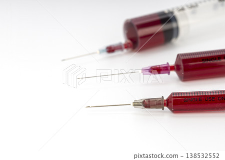 Three Single-Use Medical Syringes Filled With Dark Red Blood Arranged on a Clean White Background for Healthcare and Laboratory Concepts in Clinical Settings 138532552