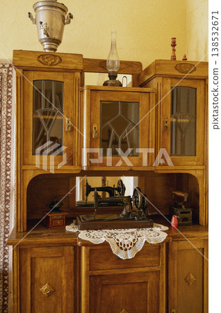Antique brown sideboard featuring an old sewing machine on its top. Domestic room interior Antique brown sideboard featuring an old sewing machine on its top. Domestic room interior 138532671