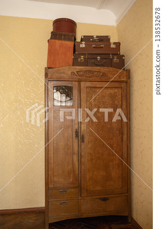 Old wooden wardrobe with vintage suitcases and hat boxes on top. Solid timber furniture Old wooden wardrobe with vintage suitcases and hat boxes on top. Solid timber furniture 138532678