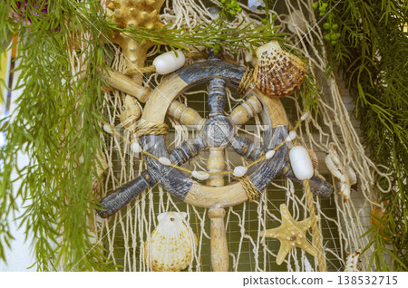 Decorative ship steering wheel with shells and a fishing net. Decorative ship steering wheel with shells and a fishing net. 138532715