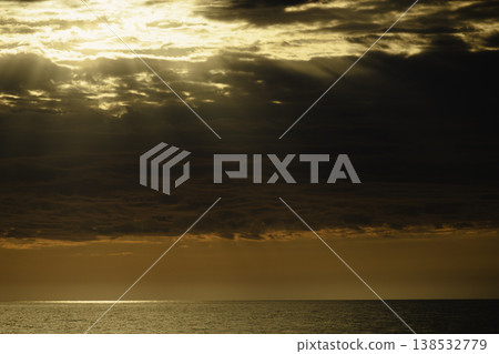 Golden sunset over calm sea with dramatic clouds and sun rays breaking through sky, warm orange horizon, tranquil ocean surface, atmospheric seascape, natural light, serene evening landscape Golden sunset over calm sea with dramatic clouds and sun rays breaking through sky, warm orange horizon, tranquil ocean surface, atmospheric seascape, natural light, serene evening landscape 138532779