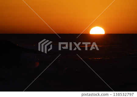 Intense red sunset over sea with bright sun and sparkling waves, dramatic reflection on water, vivid orange sky and dynamic splashes, atmospheric seascape background with strong warm tones 138532797