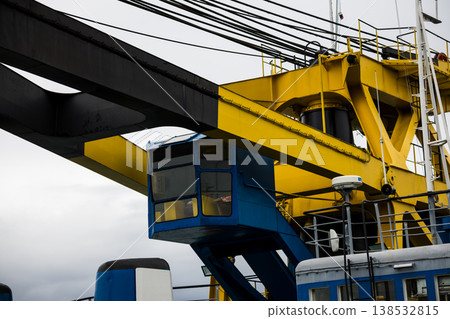 Industrial crane structure with yellow steel beams and control cabin, heavy machinery detail at port or construction site, engineering and logistics concept, modern infrastructure close-up 138532815