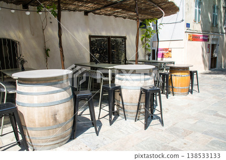 Chairs and tables lined up in a restaurant bathed in bright sunlight; a street scene on the French island of Corsica in the Mediterranean Sea. 138533133