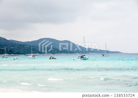 一艘休閒遊艇漂浮在科西嘉島美麗的碧綠海面上,科西嘉島是位於地中海的法國領土。 一艘休閒遊艇漂浮在科西嘉島美麗的碧綠海面上,科西嘉島是位於地中海的法國領土。 138533724