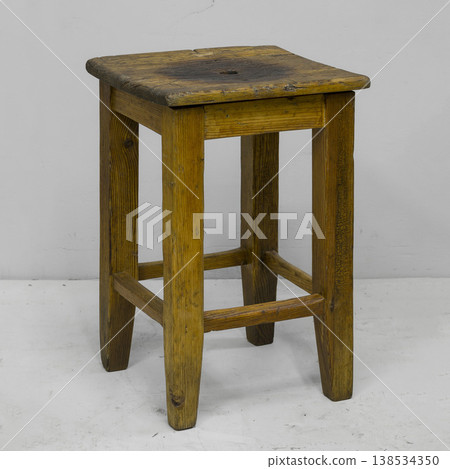 Rustic wooden stool standing alone against a simple backdrop in a calm and inviting space Rustic wooden stool standing alone against a simple backdrop in a calm and inviting space 138534350