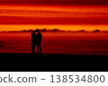 Silhouette of couple embracing at sunset by the sea, romantic scene with dramatic red sky and ocean horizon, love and relationship concept, peaceful evening atmosphere and nature background 138534800