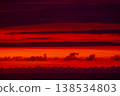 Abstract red sunset over sea horizon with layered clouds, dramatic sky background, vibrant gradient of orange and crimson tones, minimal seascape texture for design, nature and travel concept 138534803