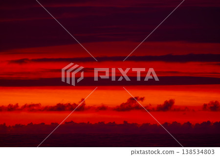Abstract red sunset over sea horizon with layered clouds, dramatic sky background, vibrant gradient of orange and crimson tones, minimal seascape texture for design, nature and travel concept 138534803