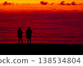 Silhouette of couple embracing at sunset by the sea, romantic scene with dramatic red sky and ocean horizon, love and relationship concept, peaceful evening atmosphere and nature background 138534804