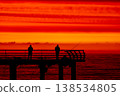 Silhouette of fisherman on pier at sunset over sea, dramatic red sky and ocean horizon, peaceful fishing scene, solitude and lifestyle concept with calm evening atmosphere 138534805