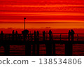 Silhouettes of people on pier at sunset over sea with dramatic red sky, group of figures against ocean horizon, evening atmosphere, lifestyle and travel concept with scenic coastal view 138534806