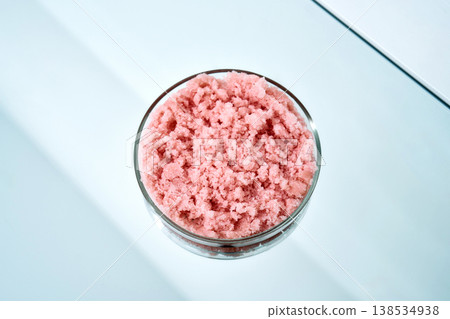 Pink sugar body scrub in glass bowl on light blue surface Pink sugar body scrub in glass bowl on light blue surface 138534938