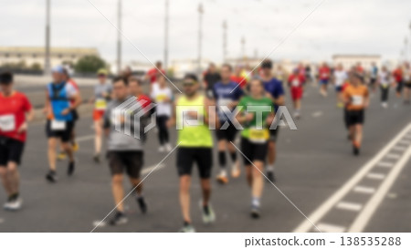 Blurry runners sprint down a wide urban road 138535288