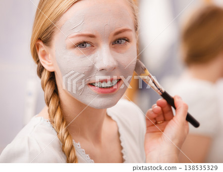 Woman applying with brush clay mud mask to her face 138535329