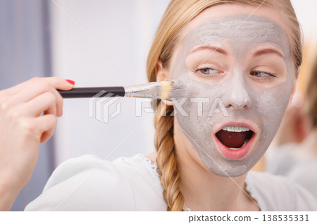 Woman applying with brush clay mud mask to her face Woman applying with brush clay mud mask to her face 138535331