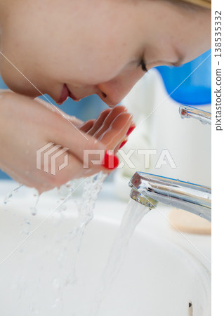 Woman washing face in bathroom. Hygiene. 138535332