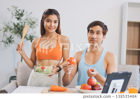 A happy couple prepares fresh vegetables, laughing and enjoying cooking a healthy meal together. A happy couple prepares fresh vegetables, laughing and enjoying cooking a healthy meal together. 138535484