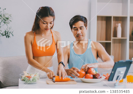A happy couple prepares fresh vegetables, laughing and enjoying cooking a healthy meal together. A happy couple prepares fresh vegetables, laughing and enjoying cooking a healthy meal together. 138535485