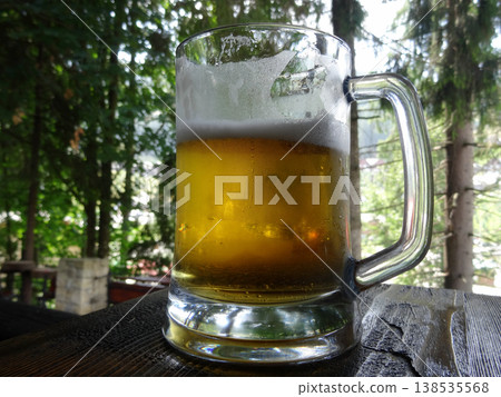 Cooled pint of beer with froth on the glass on old wood table in open air bar Cooled pint of beer with froth on the glass on old wood table in open air bar 138535568