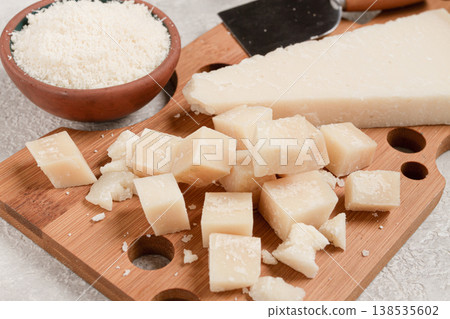 Freshly sliced and grated cheese, parmesan cheese, on a wooden chopping board, rustic style, no people Freshly sliced and grated cheese, parmesan cheese, on a wooden chopping board, rustic style, no people 138535602