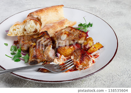 A plate with the remains of a pork kebab, there are no people. A plate with the remains of a pork kebab, there are no people. 138535604
