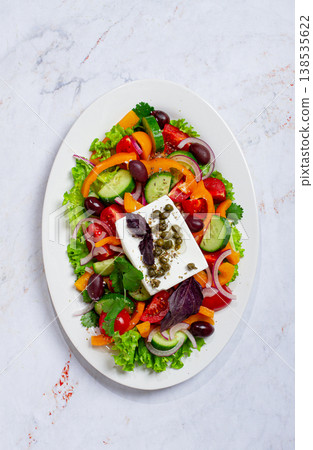 Greek salad, with vegetables and feta cheese, served on a white plate, no people. 138535622