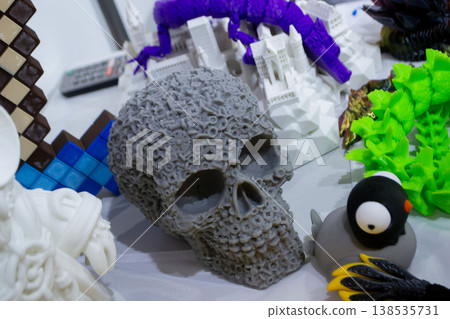 3D printed different art objects. Objects printed on 3D printer from melted colored plastic. Model gray skull created on 3D printer from threads of molten plastic. Modern new additive technologies 138535731