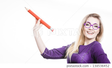 Smiling woman holds big pencil in hand Smiling woman holds big pencil in hand 138536452