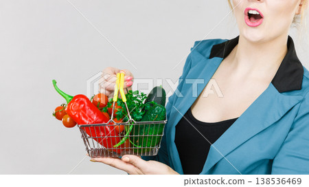Woman holds shopping basket with vegetables Woman holds shopping basket with vegetables 138536469