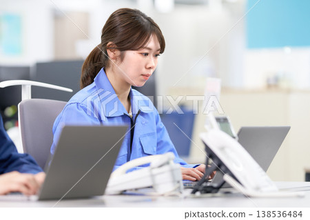 一名身穿工作服的工廠工人正在進行資料輸入。 一名身穿工作服的工廠工人正在進行資料輸入。 138536484