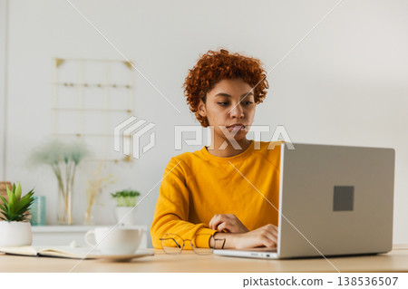 African American girl using laptop at home office looking at screen typing chatting reading writing email. Young woman having virtual meeting online chat video call conference. Work learning from home 138536507