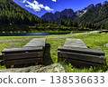 Wooden loungers by a mountain lake with alpine panorama 138536633