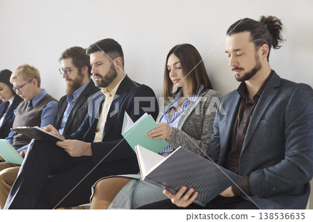 Closeup of job applicants waiting for interview, reviewing resumes in office 138536635