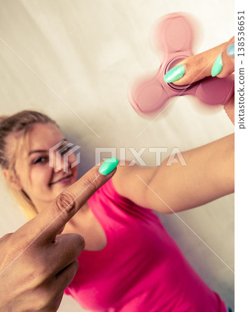 Woman playing fidget spinner Woman playing fidget spinner 138536651