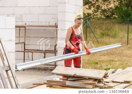 Woman carrying gutter on construction site Woman carrying gutter on construction site 138536669