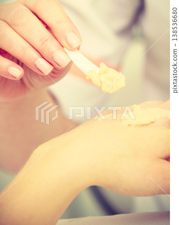 Woman applying cream on hand using spatula 138536680