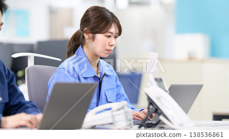 A scene of factory staff in work clothes performing data entry. A scene of factory staff in work clothes performing data entry. 138536861