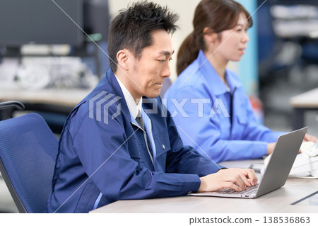 一名身穿工作服的工廠工人正在進行資料輸入。 138536863