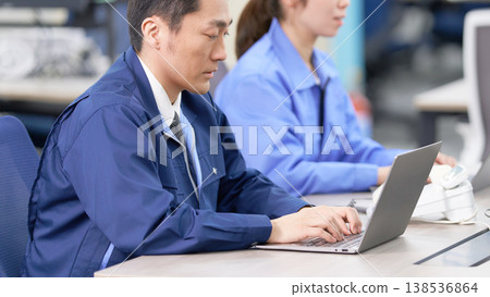 A scene of factory staff in work clothes performing data entry. A scene of factory staff in work clothes performing data entry. 138536864