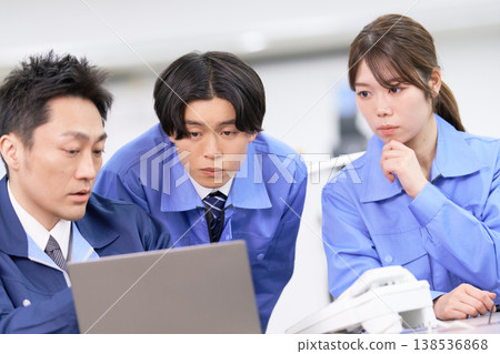 三個穿著工作服的人,兩男兩女,正圍著一台筆記型電腦認真地討論著什麼。 三個穿著工作服的人,兩男兩女,正圍著一台筆記型電腦認真地討論著什麼。 138536868