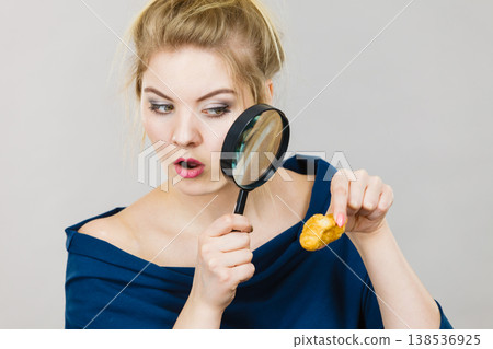 Woman holding magnifying glass investigating bread 138536925