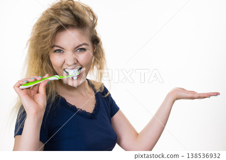 Woman brushing teeth holds open hand Woman brushing teeth holds open hand 138536932