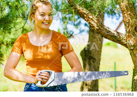 Female cuts branches of tree, using saw Female cuts branches of tree, using saw 138536968