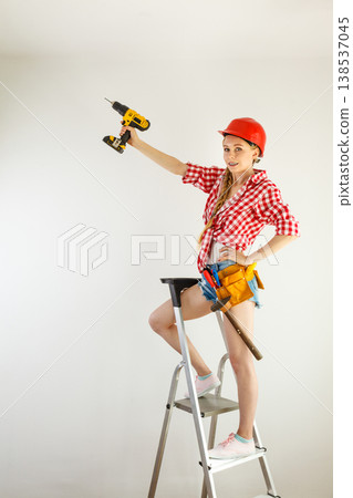 Woman using drill on ladder Woman using drill on ladder 138537045