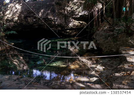 Crystal clear cenote water surrounded by rocky walls and vines 138537454
