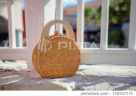 Round woven straw basket bag by white railing Round woven straw basket bag by white railing 138537535