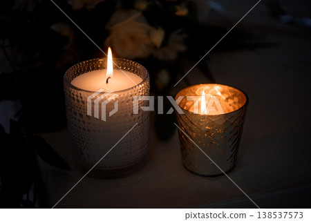 Two decorative candles glowing in glass holders Two decorative candles glowing in glass holders 138537573
