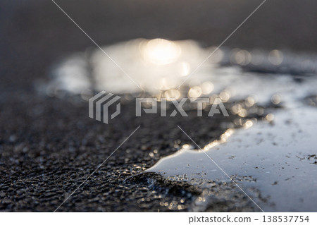 Puddles on the asphalt glistening in the setting sun Puddles on the asphalt glistening in the setting sun 138537754